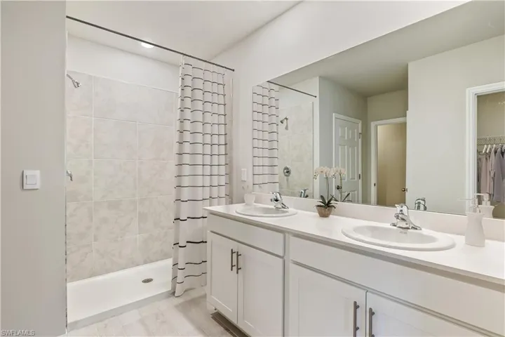 This home is virtually staged. Full bath featuring a stall shower, double vanity, and a walk in closet