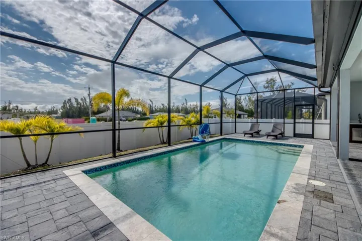 View of swimming pool featuring a sunroom, glass enclosure, a fenced backyard, and a patio