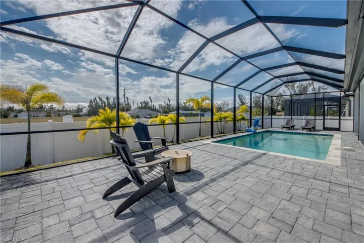 View of swimming pool featuring a sunroom, glass enclosure, and a patio area