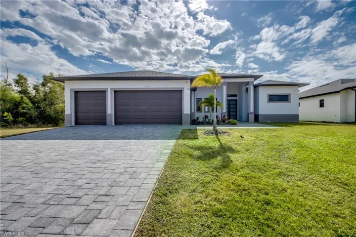 Prairie-style home with decorative driveway, a front lawn, stucco siding, and an attached garage