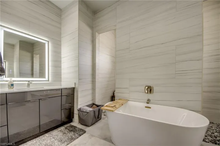Full bath with tile walls, vanity, and a freestanding tub