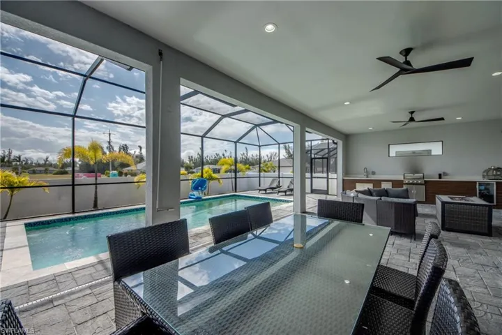 Swimming pool with an outdoor living space, outdoor dining space, a patio, a sunroom, and glass enclosure