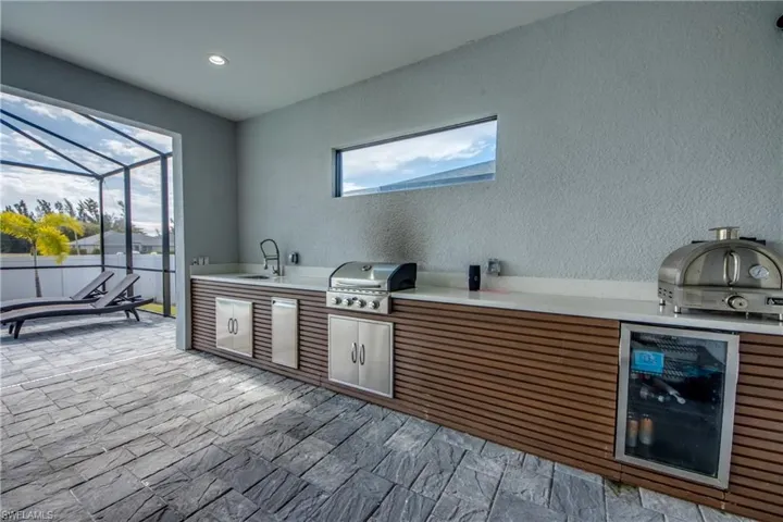 Bar area with a sunroom, brown cabinetry, light stone countertops, a textured wall, and recessed lighting