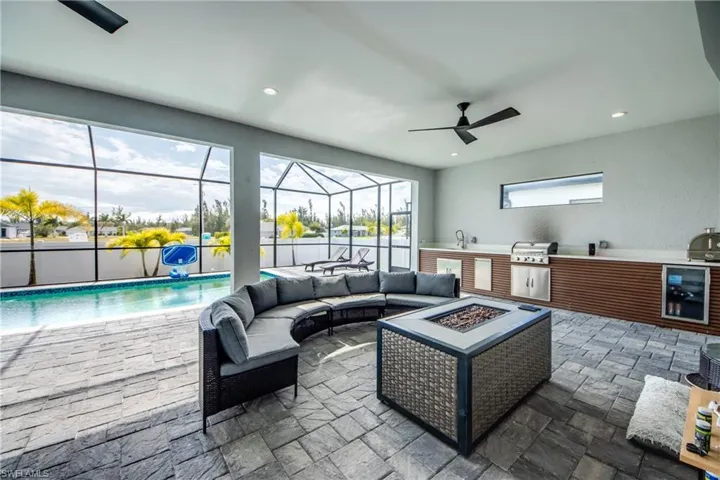 Living room with a sunroom, wine cooler, ceiling fan, stone finish floors, and recessed lighting
