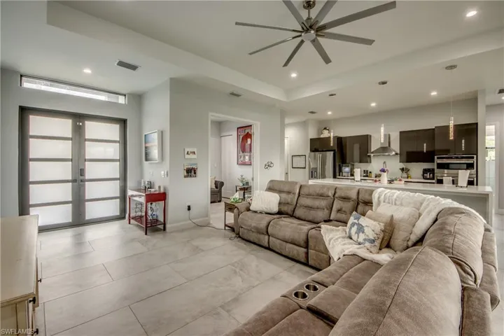 Living room with recessed lighting, french doors, ceiling fan, and a tray ceiling