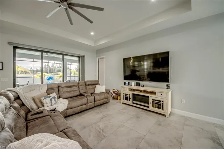 Living area with a raised ceiling, ceiling fan, and recessed lighting