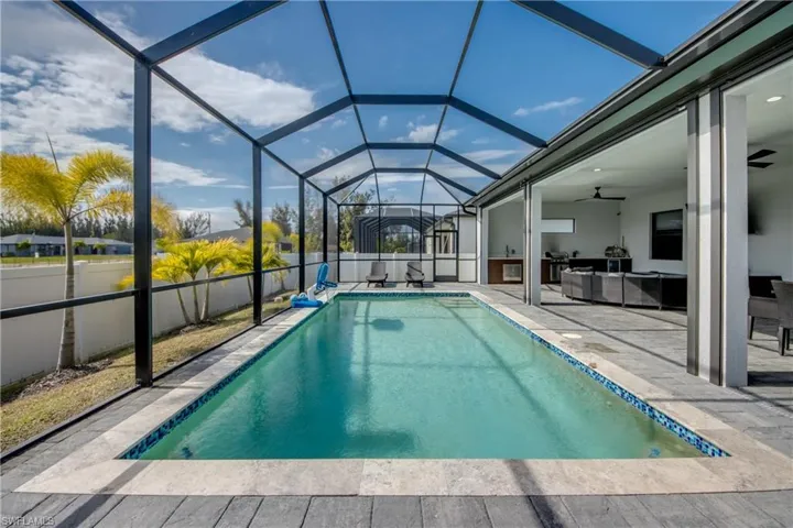 Outdoor pool featuring a sunroom, glass enclosure, a patio, and an outdoor hangout area