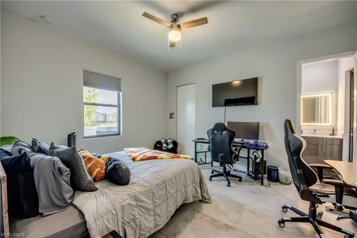 Bedroom with an office area, connected bathroom, a ceiling fan, and a closet