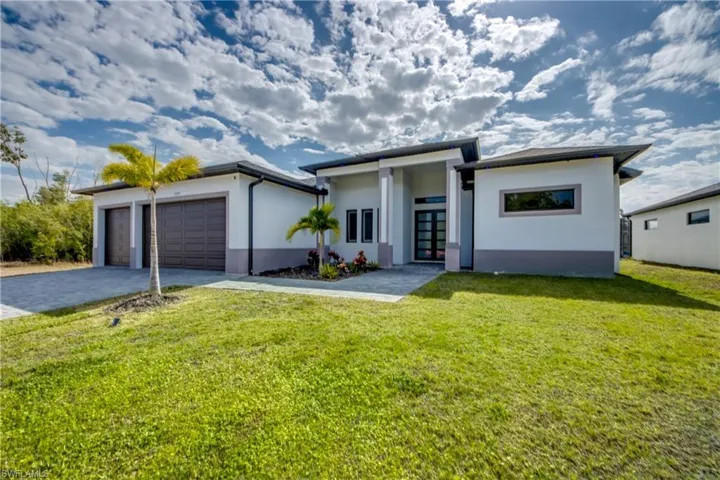 Prairie-style home featuring stucco siding, decorative driveway, a front lawn, an attached garage, and french doors