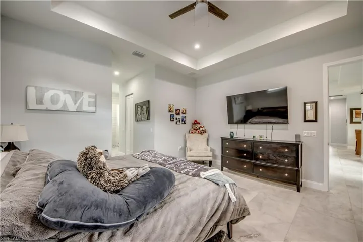 Bedroom with a raised ceiling, recessed lighting, and a ceiling fan