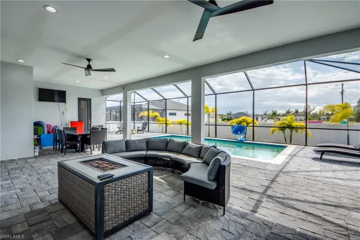 View of patio / terrace featuring an outdoor living space with a fire pit, outdoor dining space, ceiling fan, a sunroom, and a lanai