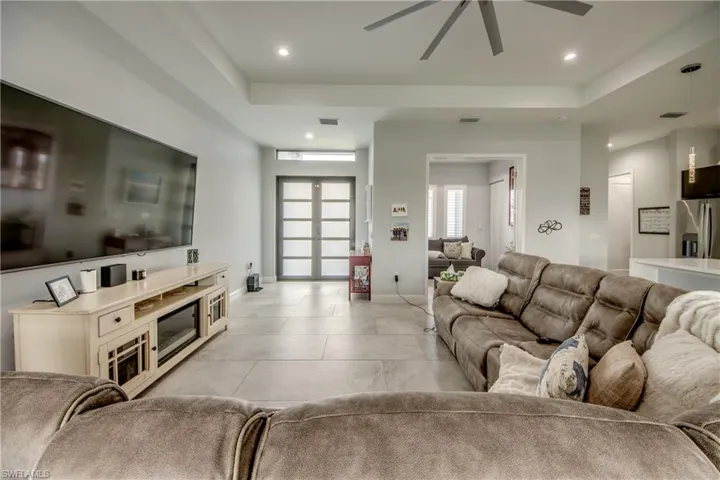 Living room with a raised ceiling, ceiling fan, and recessed lighting