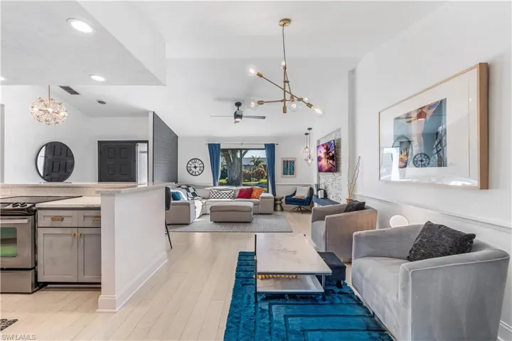 Living room featuring ceiling fan with notable chandelier and light hardwood / wood-style flooring