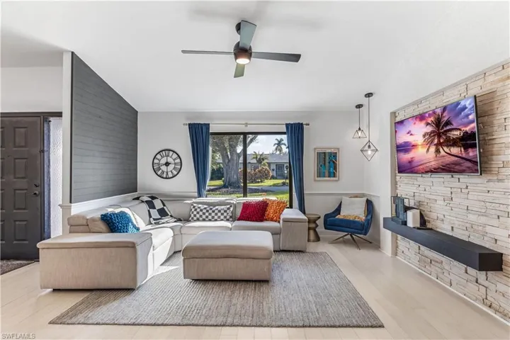 Living room with light wood-type flooring, vaulted ceiling, and ceiling fan