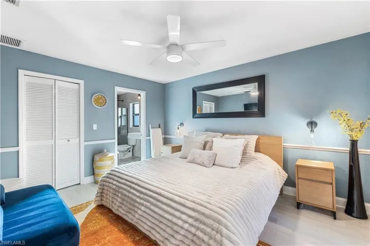 Bedroom featuring ceiling fan, a closet, ensuite bath, and light hardwood / wood-style flooring