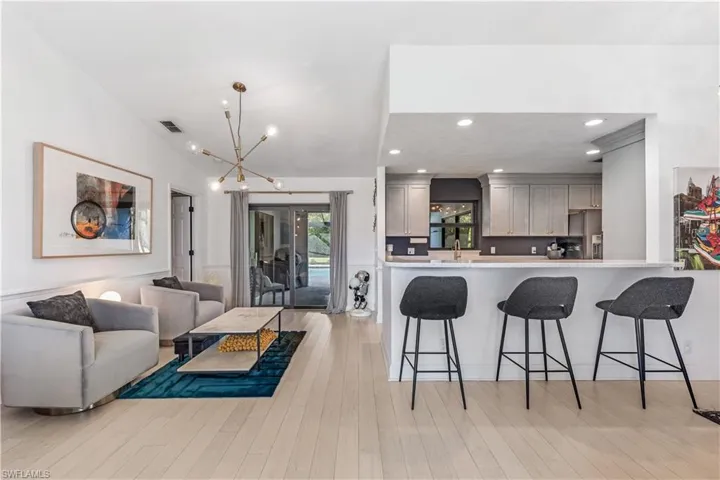 Kitchen featuring kitchen peninsula, gray cabinetry, decorative light fixtures, a chandelier, and light hardwood / wood-style floors