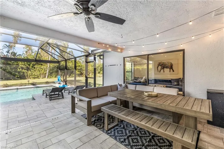 View of patio with glass enclosure, an outdoor living space, and ceiling fan