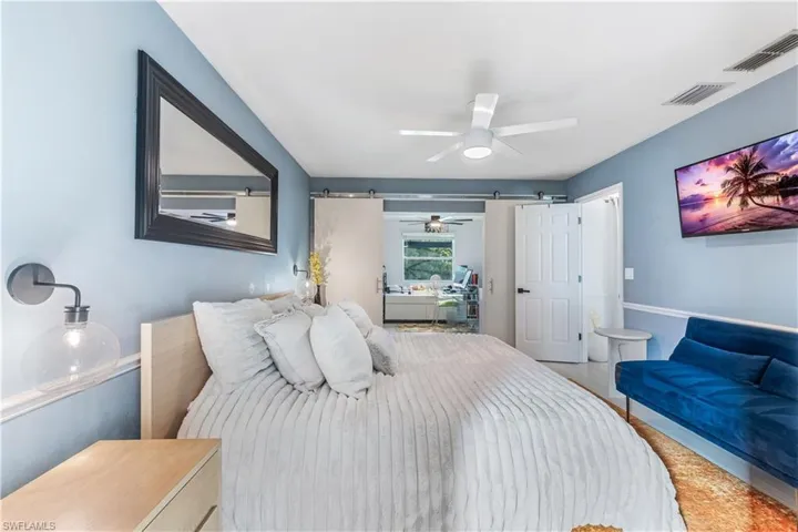 Bedroom featuring a barn door, ceiling fan, and hardwood / wood-style floors