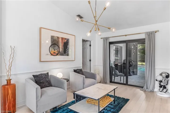 Living room featuring light wood-type flooring, lofted ceiling, and an inviting chandelier