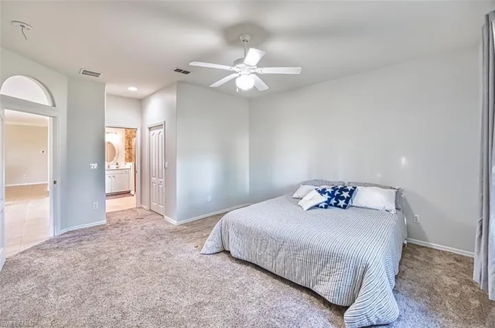 Bedroom featuring carpet floors, ceiling fan, and ensuite bathroom
