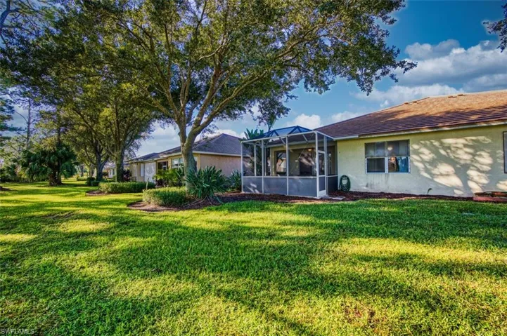 Back of property with a sunroom, a lawn, a lanai, and stucco siding