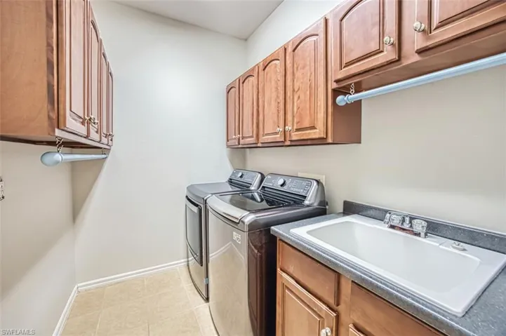 Laundry room with washer and clothes dryer, light tile patterned floors, and cabinet space