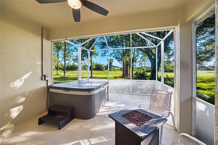 Sunroom / solarium with a fire pit, a ceiling fan, a patio area, and a jacuzzi