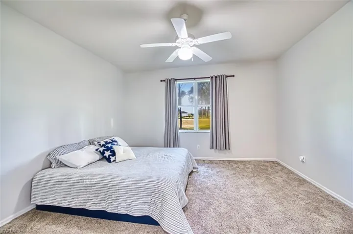 Carpeted bedroom with a ceiling fan and baseboards