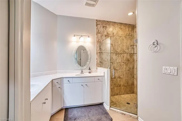 Bathroom with a stall shower, vanity, light tile patterned flooring, and recessed lighting