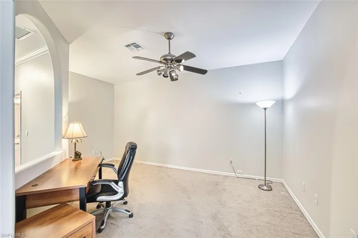 Carpeted den featuring arched walkways and ceiling fan