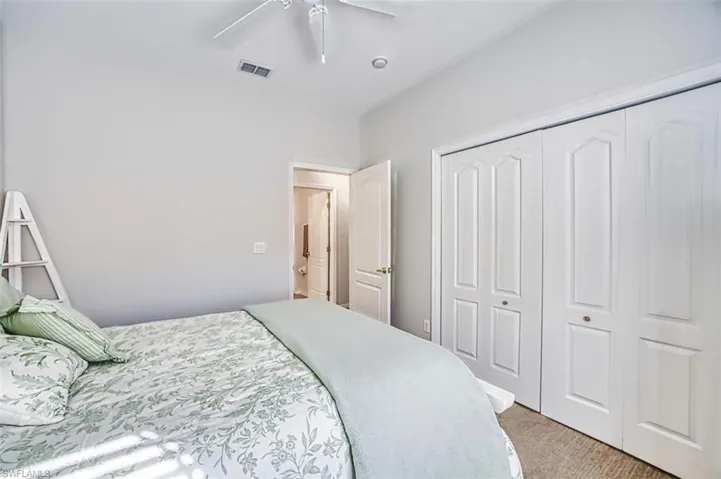 Bedroom with light carpet, a ceiling fan, and a closet