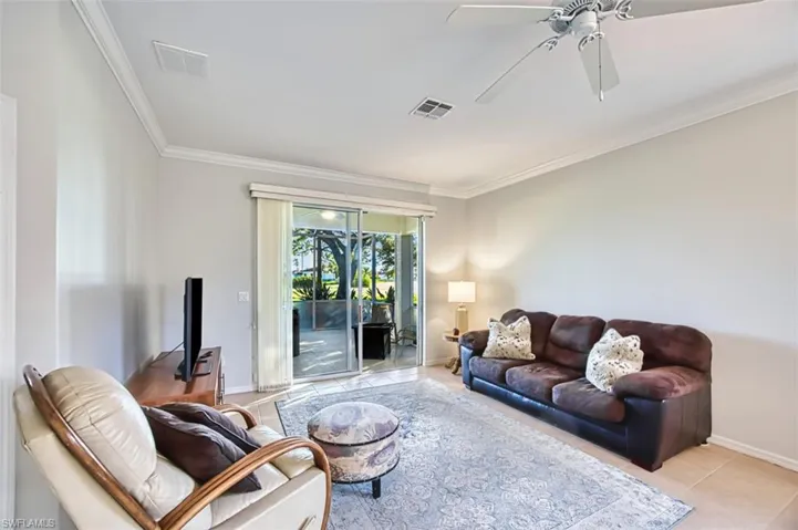 Living room with ornamental molding, ceiling fan, and light tile patterned flooring