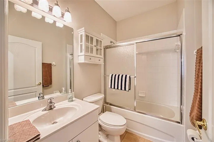 Bathroom featuring shower / bath combination with glass door, vanity, and light tile patterned flooring