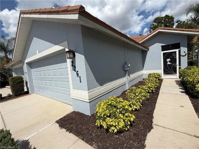 View of side of home with a garage, driveway, and stucco siding