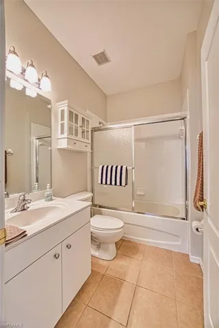 Bathroom featuring light tile patterned floors, vanity, and combined bath / shower with glass door