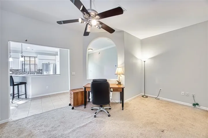 Office space with light tile patterned floors, light colored carpet, ceiling fan, and crown molding