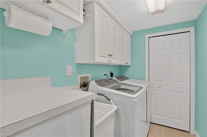 Laundry area featuring white cabinetry, a built-in utility sink, and bi-fold doors