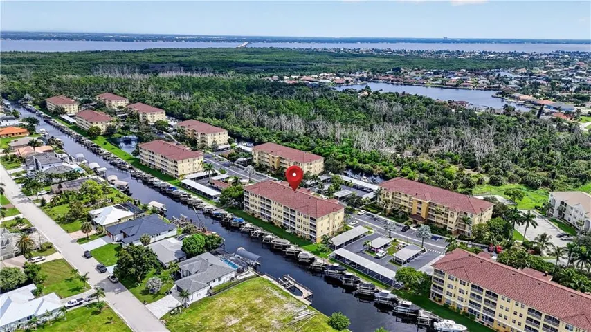 Waterfront community featuring multiple condominium buildings with tile roofs, covered parking, and boat slips