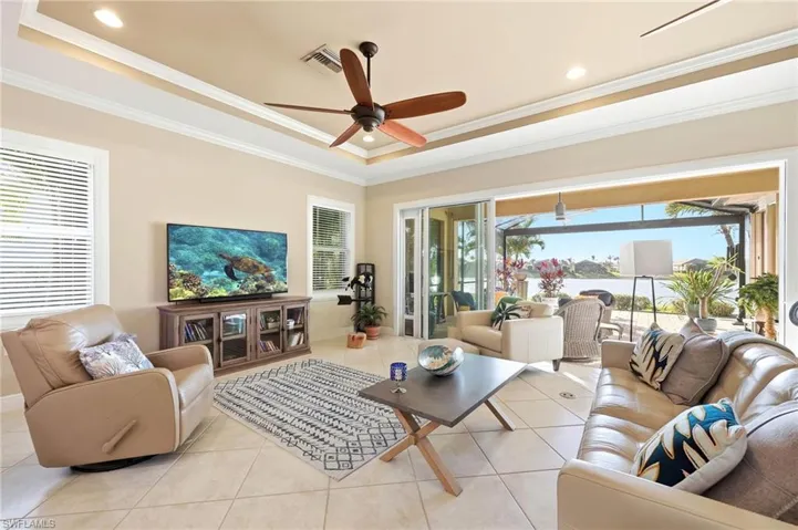 Living room featuring ceiling fan, recessed lighting, a raised ceiling, light tile patterned floors, and crown molding