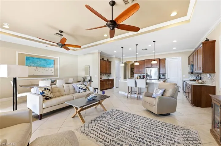 Living area featuring a tray ceiling, arched walkways, ceiling fan, recessed lighting, and crown molding