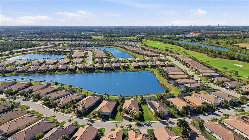 Aerial view of residential area featuring a nearby body of water and a golf club