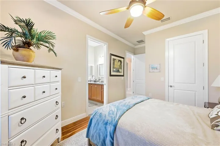 Bedroom featuring crown molding, light wood-type flooring, a ceiling fan, and connected bathroom