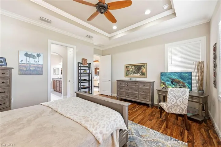 Bedroom with crown molding, ceiling fan, dark wood-type flooring, a raised ceiling, and recessed lighting