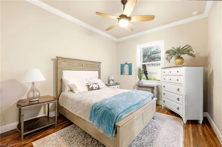 Bedroom featuring ornamental molding, dark wood finished floors, and ceiling fan
