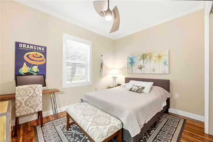 Bedroom with ornamental molding, dark wood-type flooring, and a ceiling fan