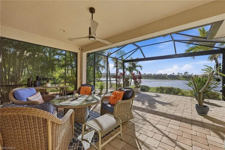 View of patio featuring glass enclosure, a sunroom, a ceiling fan, and a water view