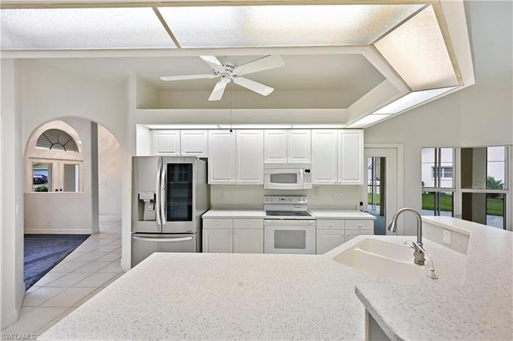 The kitchen has bright countertops and cabinets as well as a pantry