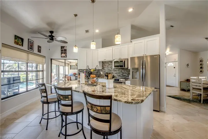 Kitchen featuring pendant lighting, decorative backsplash, white cabinets, and appliances with stainless steel finishes