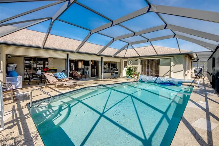 View of swimming pool featuring a patio and glass enclosure