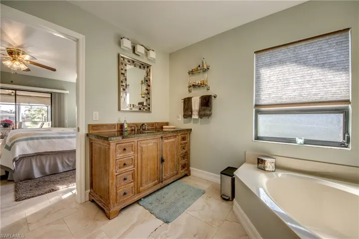 Bathroom with vanity, a washtub, and ceiling fan